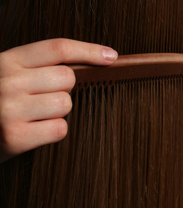 Hand examining hair strands during the post-transplant shedding phase