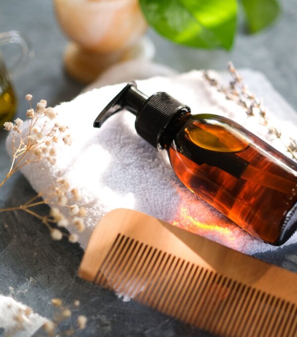 Amber pump bottle and wooden comb for a gentle hair and scalp aftercare routine